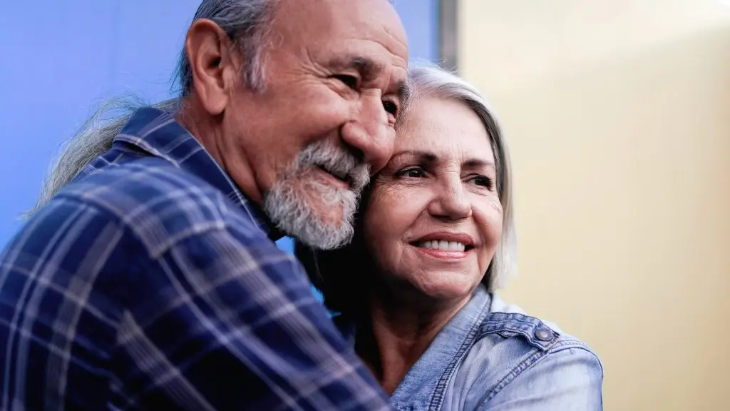 An older man and woman smiling and embracing.